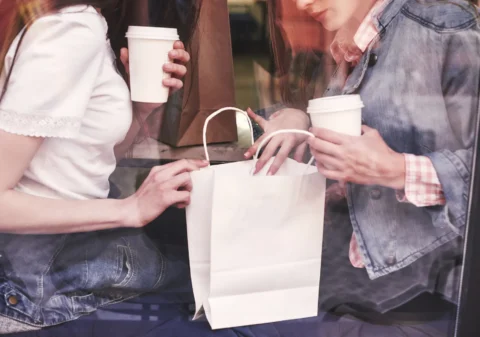 two-beautiful-young-women-sitting-cafe-drinking-coffee-having-pleasant-conversation-after-shopping